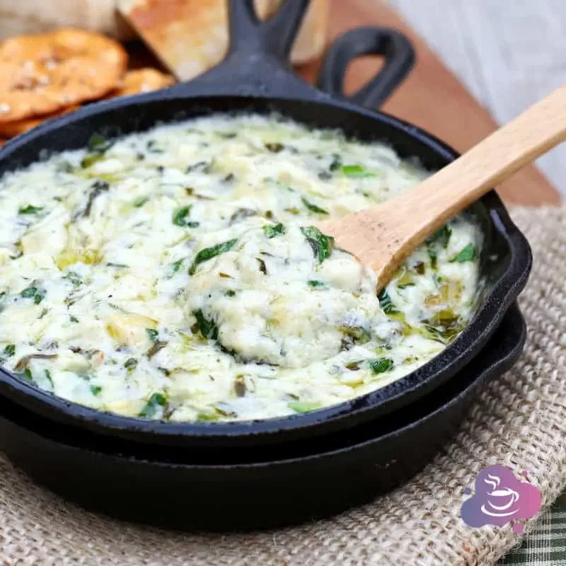 Käse-Spinat Dip mit knusprigem Brot in rustikaler Gusseisenpfanne, perfekt zum Teilen.