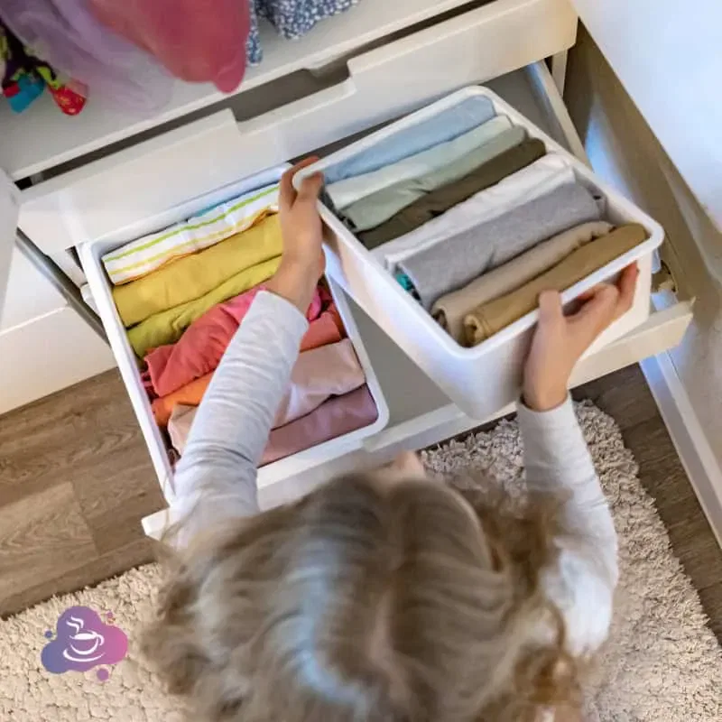 Kind, ordentliches Kinderzimmer beim Aufräumen und Kleidung sortieren für mehr Unabhängigkeit.