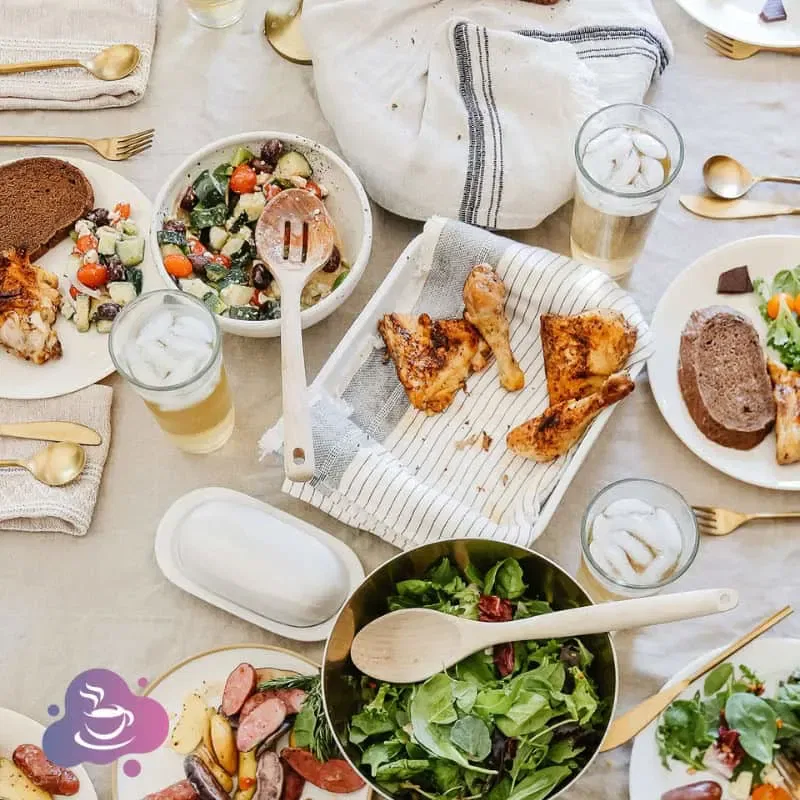 Eleganter gedeckter Tisch mit frischen Salaten, gegrilltem Fleisch und rustikalem Brot für gesellige Mahlzeiten.