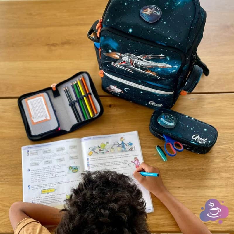 Kindergarten kind lernt kreativ mit buntem Schulzubehör und Abenteuerrucksack.