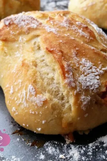 Frisch gebackenes Brötchen auf Backblech mit Mehl bestäubt, rustikal und einladend.