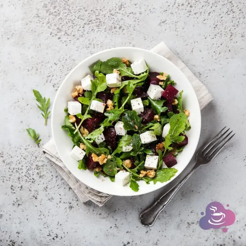 Frischer Beetsalat mit Feta, Nüssen und Kräutern auf weißem Teller, gesund und lecker.