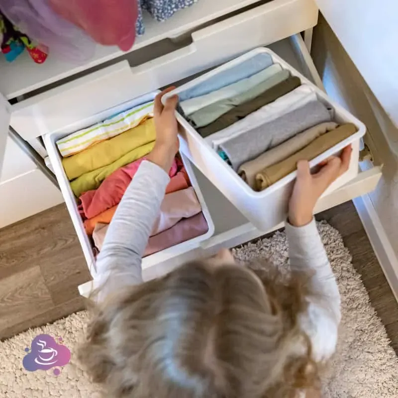 Kind, ordentliches Kinderzimmer beim Aufräumen und Kleidung sortieren für mehr Unabhängigkeit.