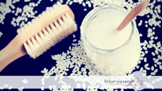 Reiswasser im Glas mit Reiskörnern und Bürste.