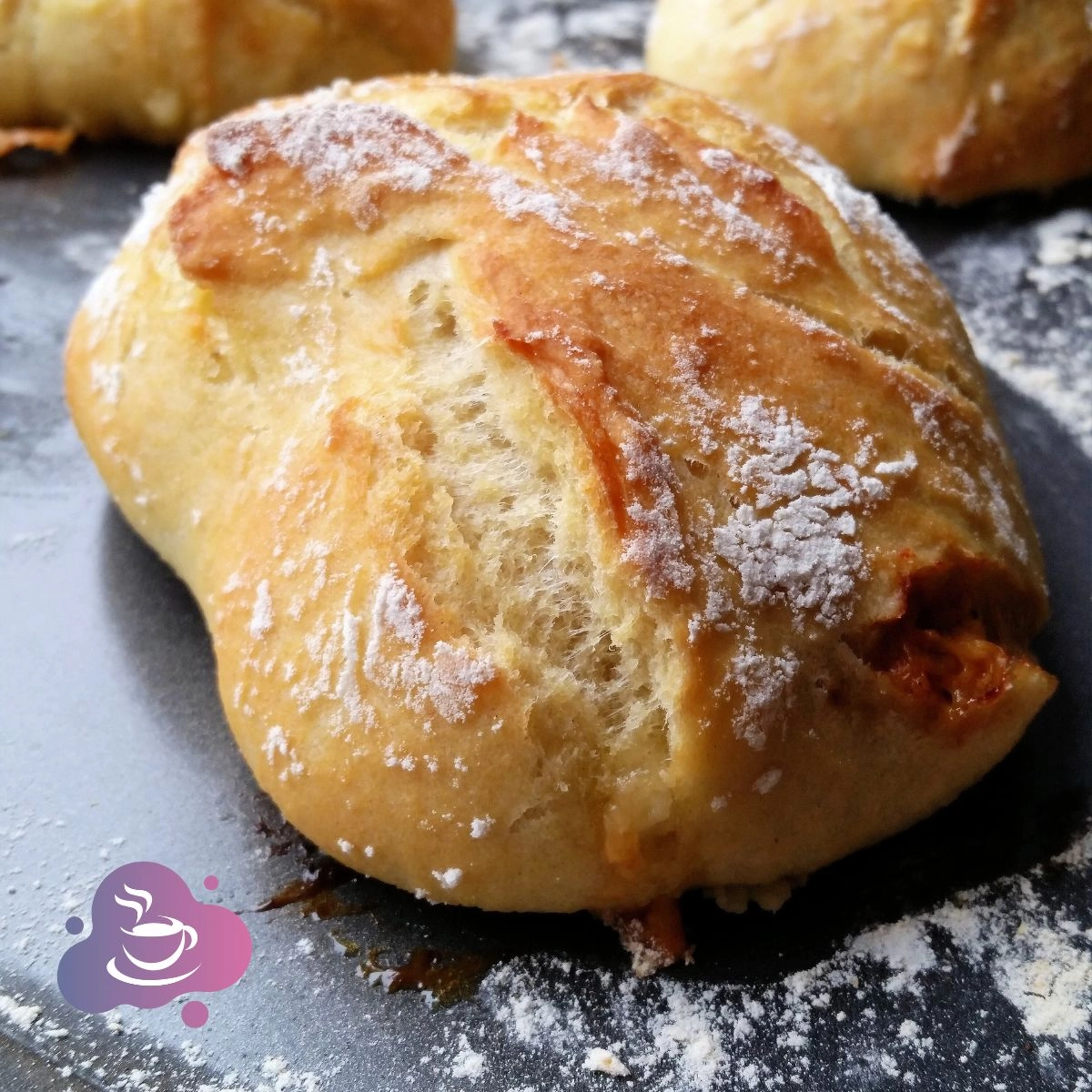 Frisch gebackenes Brötchen auf Backblech mit Mehl bestäubt, rustikal und einladend.