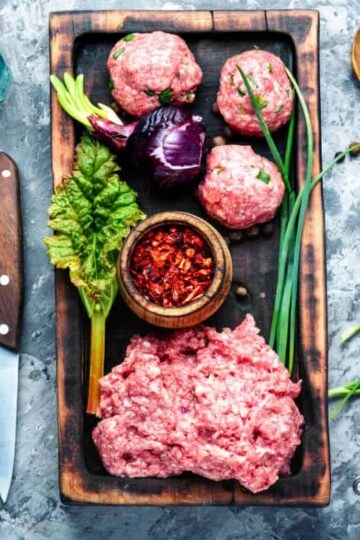 Frisches rohes Hackfleisch mit Gemüse, Kräutern und Gewürzen für die Zubereitung.
