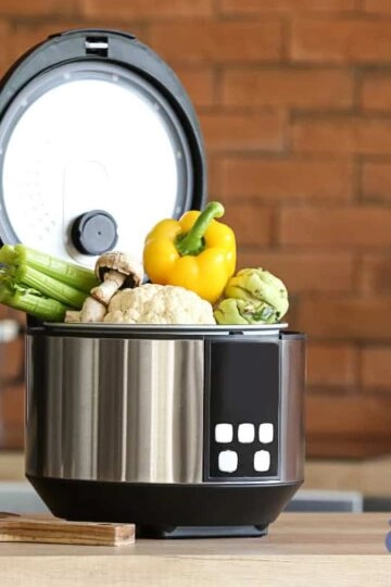 Moderner elektrischer Reiskocher mit frischem Gemüse in stilvoller Küchendekoration.