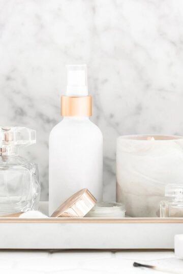 Elegante Beauty- und Pflegeprodukte auf minimalistischem Tablett mit Duftkerze und hochwertigem Design.