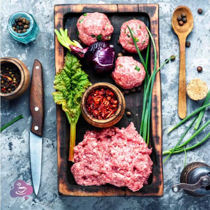 Frisches rohes Hackfleisch mit Gemüse, Kräutern und Gewürzen für die Zubereitung.
