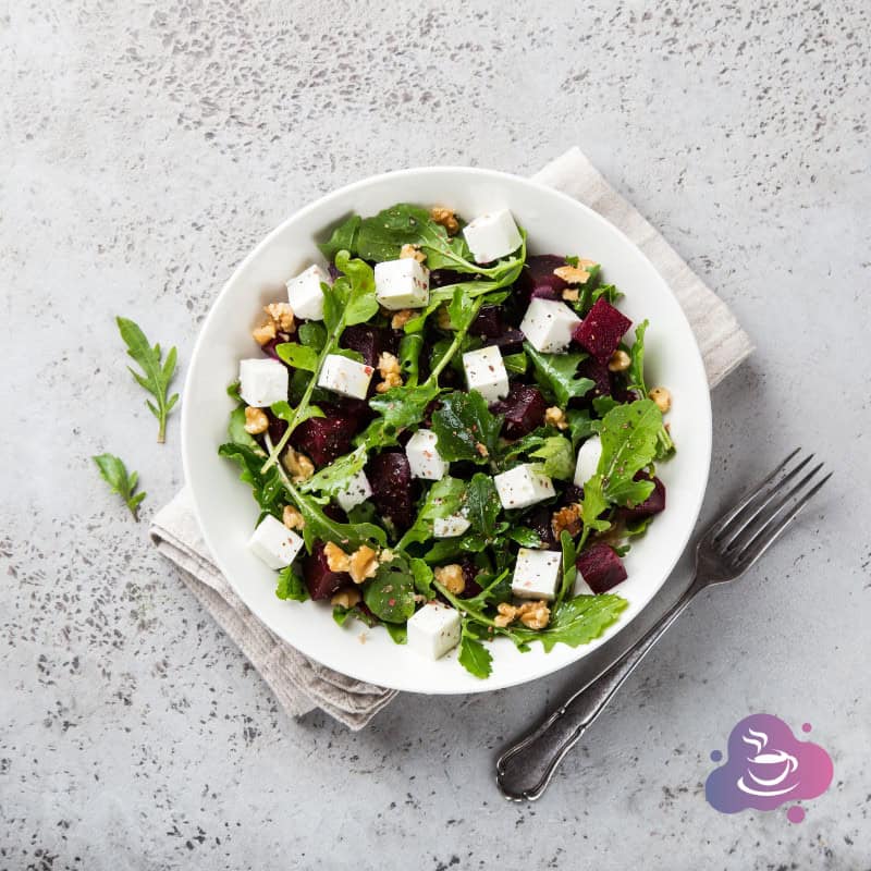Frischer Beetsalat mit Feta, Nüssen und Kräutern auf weißem Teller, gesund und lecker.