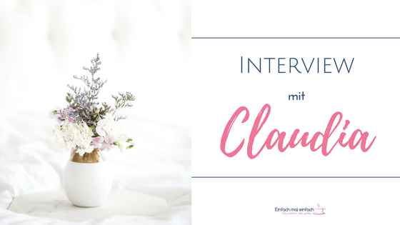 Weiße Vase mit lila und weißen Blumen auf Marmortablett vor hellem Hintergrund. Text:"Interview mit Claudia"